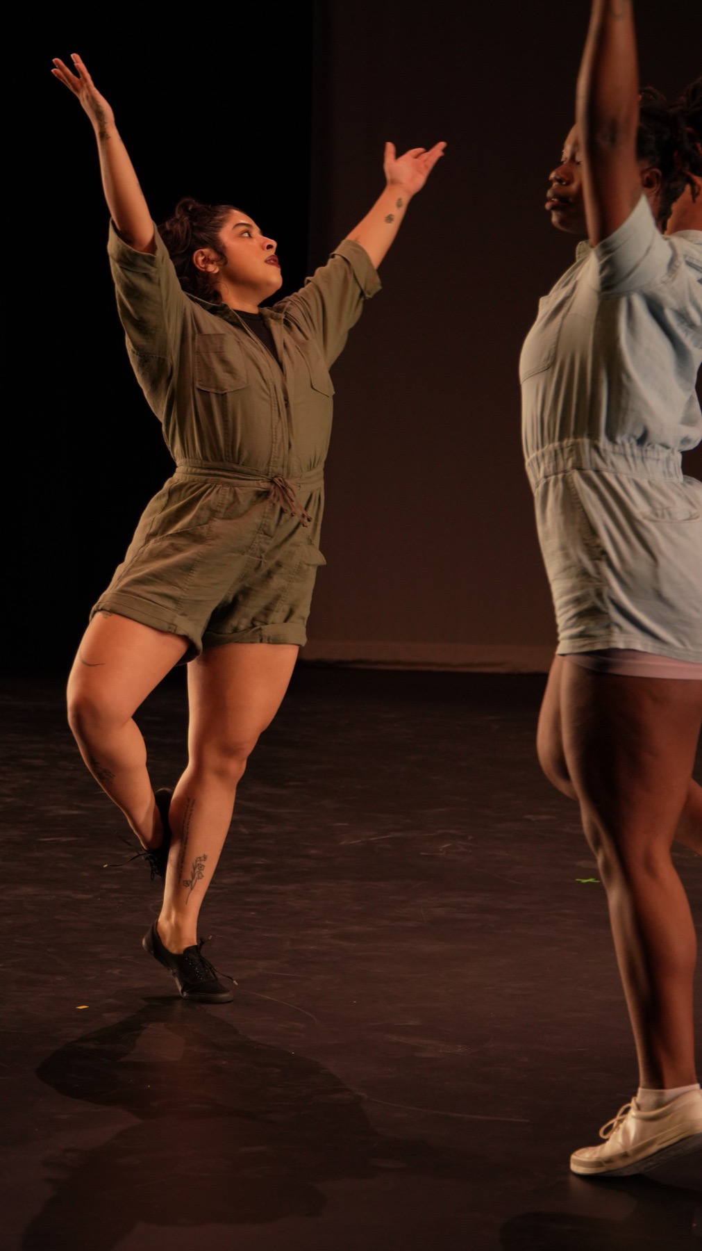 A student mid-turn with arms raised during ballet class